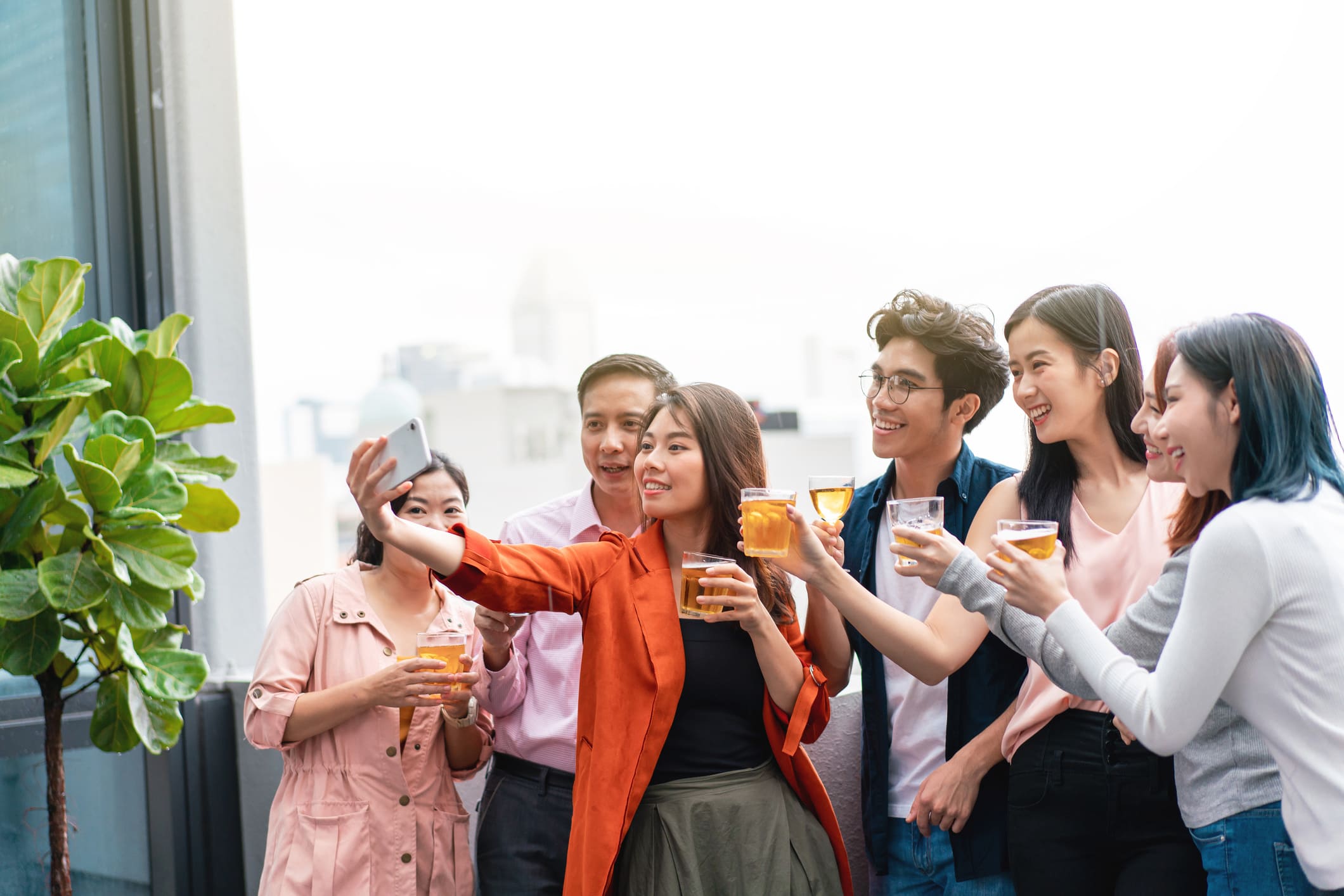 group of asian friends posing with a selfie photo holding cup of beer